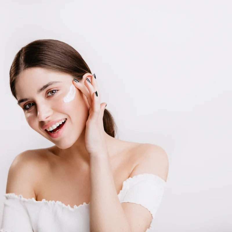 Woman with fresh, glowing skin touching her cheek